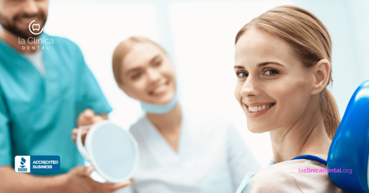 Mujer sonriendo en silla dental con personal de La Clínica Dental, reflejando atención dental y tecnología avanzada en tratamientos de coronas.