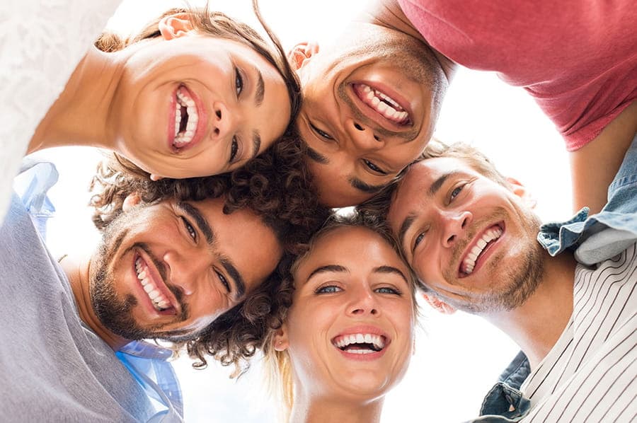 Grupo de amigos sonriendo juntos, destacando sonrisas brillantes, reflejando la importancia de tratamientos estéticos dentales en La Clínica Dental Polanco V.