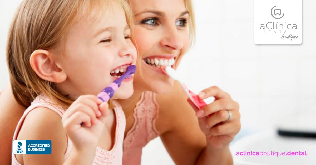 Mujer y niña cepillándose los dientes, promoviendo la higiene dental infantil en La Clínica Dental Guadalajara.