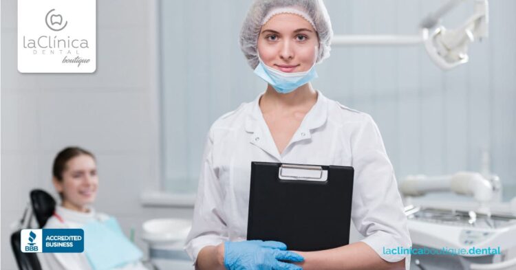 Mujer dentista en la Clínica Dental Guadalajara sosteniendo un portafolios, con paciente en silla dental de fondo, resaltando servicios y oportunidades laborales en el sector dental.