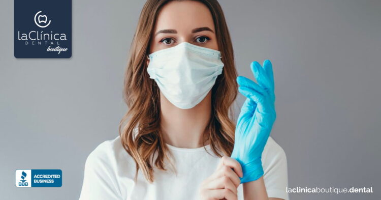 Mujer con mascarilla y guantes de látex, preparándose para atención dental en La Clínica Dental Guadalajara.