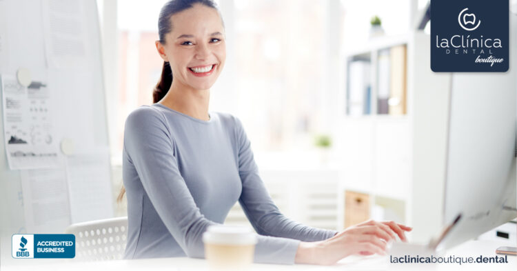 Mujer sonriente en un entorno de oficina, representando la atención al cliente en La Clínica Dental Guadalajara, con logo de la clínica y símbolo de negocio acreditado.